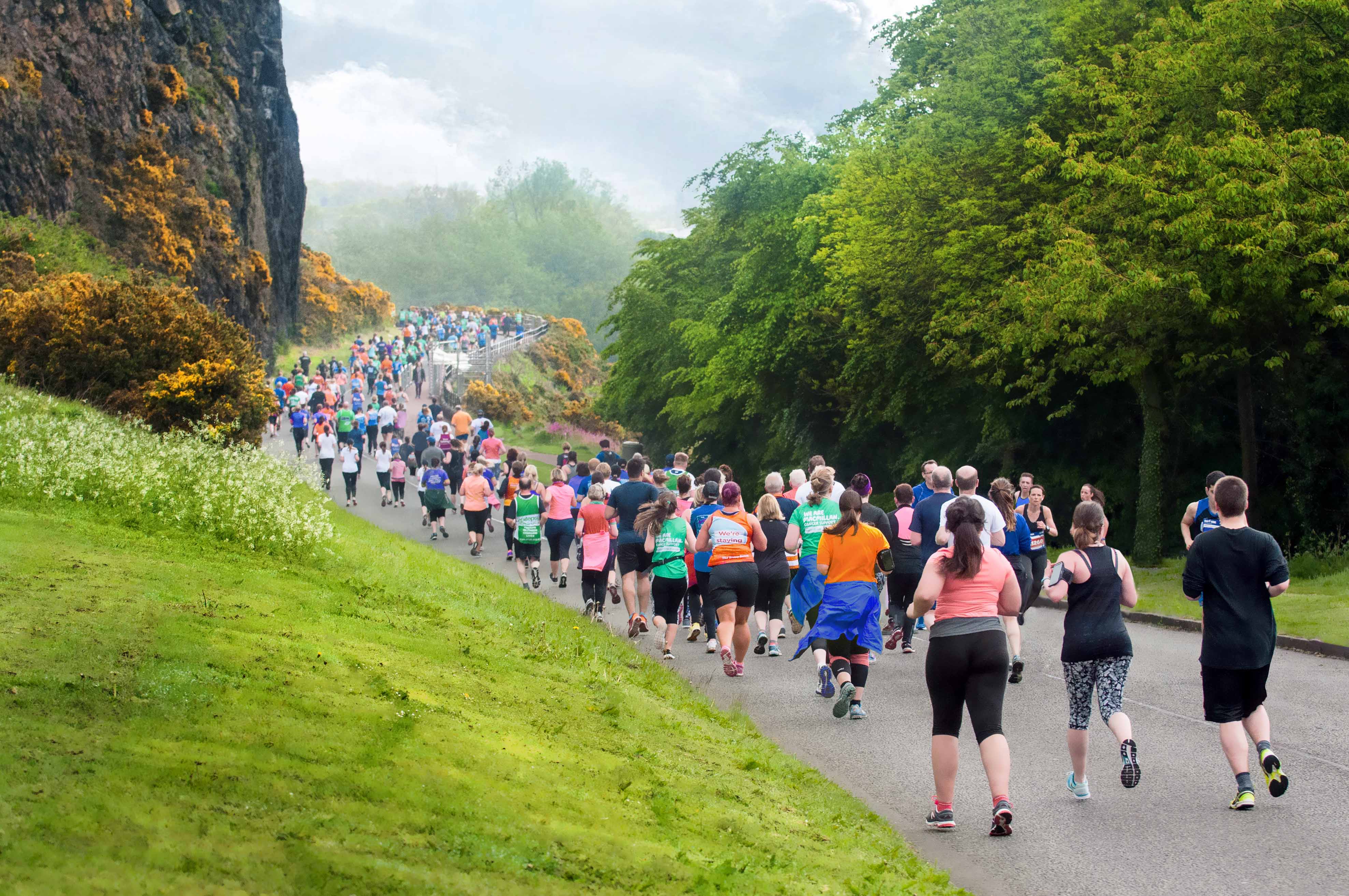 Edinburgh 5km Group of people running in sports gear beside beautiful green Edinburgh hills