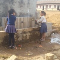 Two girls washing hands with tap